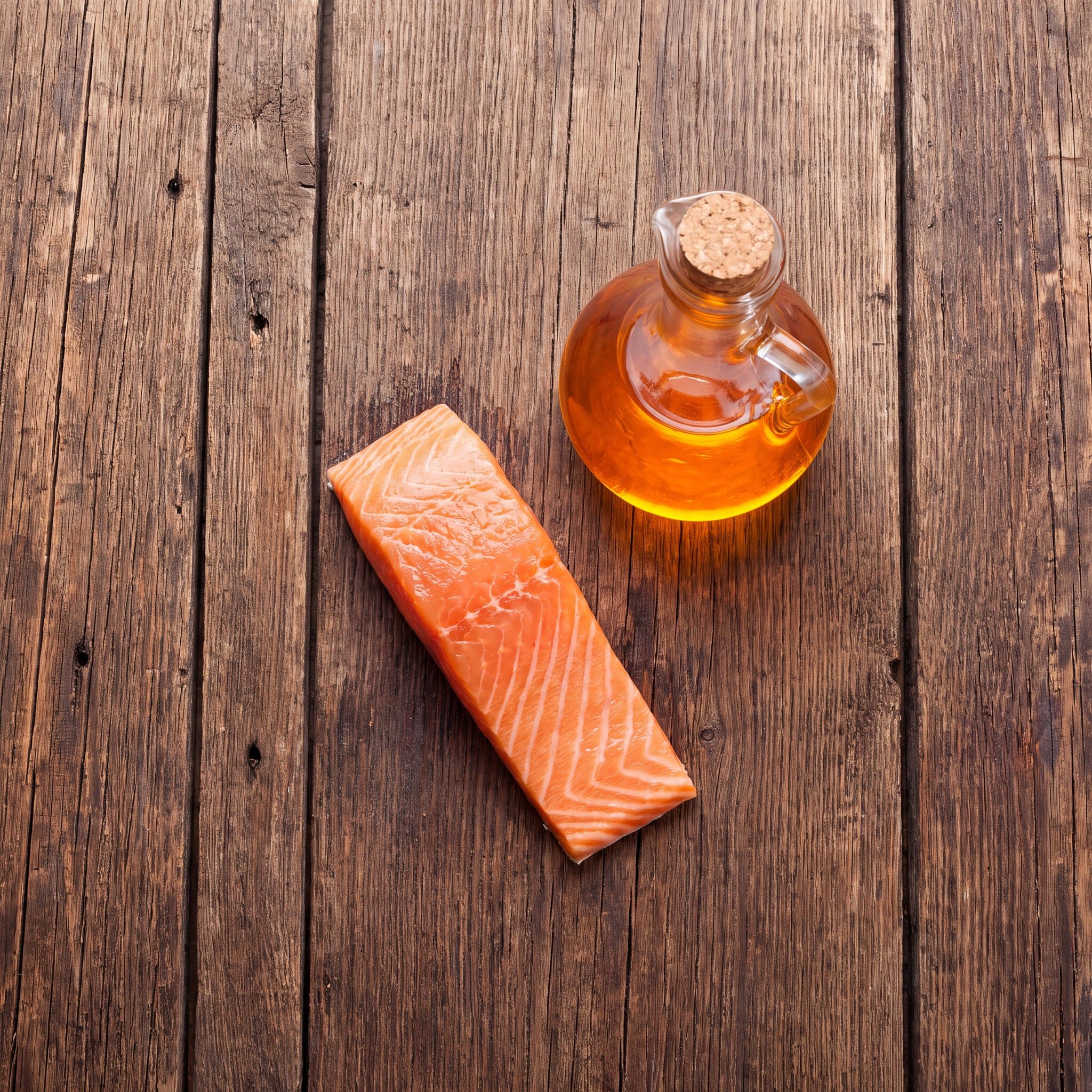 Suroviny oleje Wild Salmon Oil na dřevěném stole: losos a karafa lososového oleje